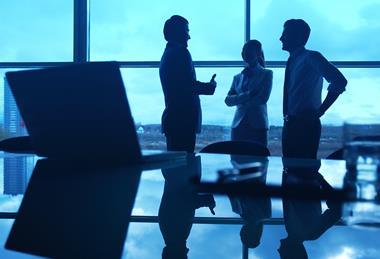 stock-photo-three-office-workers-interacting-by-the-window-with-their-workplace-in-front-162320312_CP