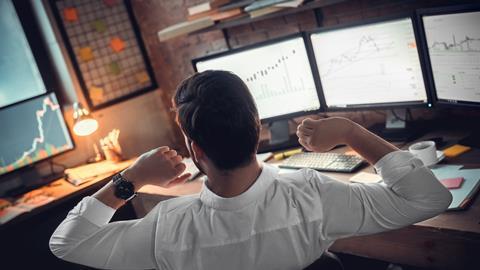 Rear view of stock trader stretching hands at workplace